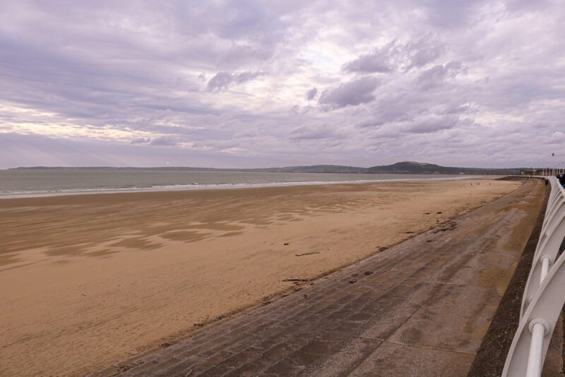 Aberavon Beach just before sunset in autumn with a grey cloudy sky and a long stretch of empty sandy beach