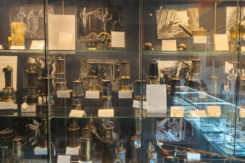 glass display with shelves full of old minin lamps and other equipment at the south wales mining museum