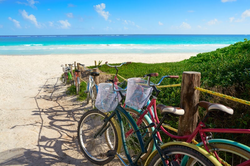 lots of different colourted bikes on a white sandy beach with turqouise sea beyond