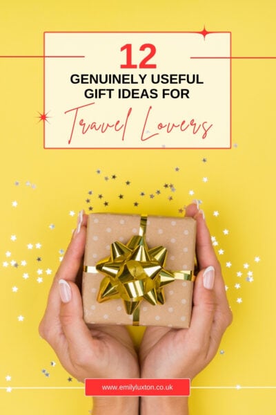 Two hands holding a gift wrapped in brown paper with a gold ribbon over a bright yellow background. Text reads !12 genuinely useful gift ideas for travel lovers"