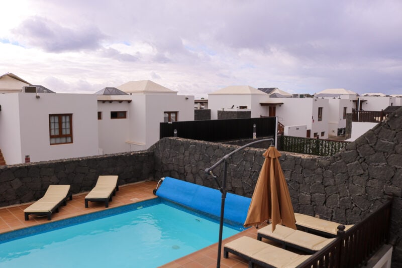 small outdoor swimming pool on a terrace outside a villa with sun loungers around it on a cloudy day with grey sky