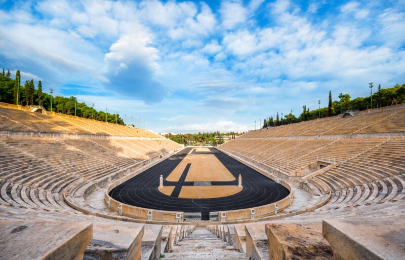 long oval-shaped stadium built in ancient greek style with tiered marble seating around the outside and a running track inside  
