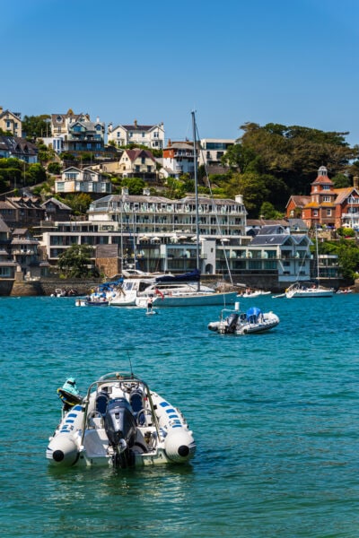 grey and blue RIB motorboat in a blue river with the small town of Salcombe on a hillside in the background