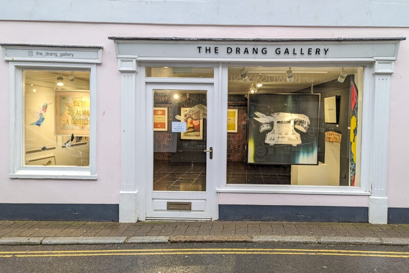 exterior of The Drang Gallery in Salcombe with pink walls and several paintings in the windows