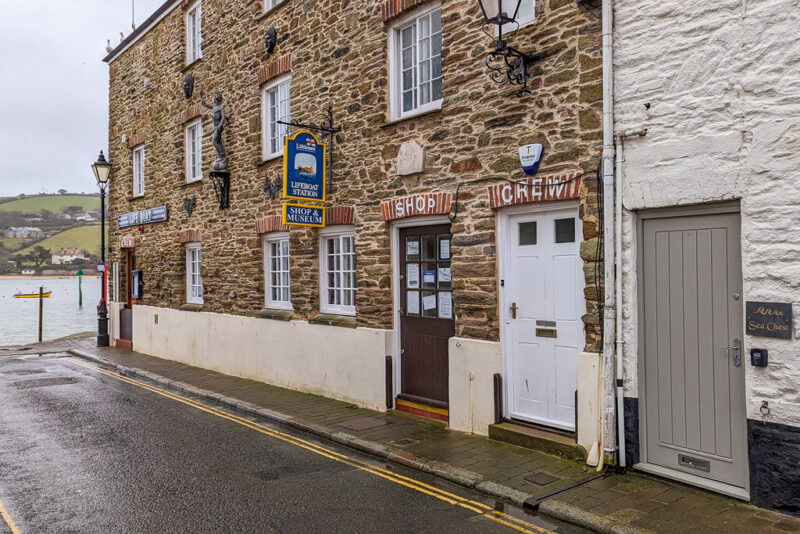 exterior of a brown stone cottage with two doors and a sign that says RNLI Shop & Museum.