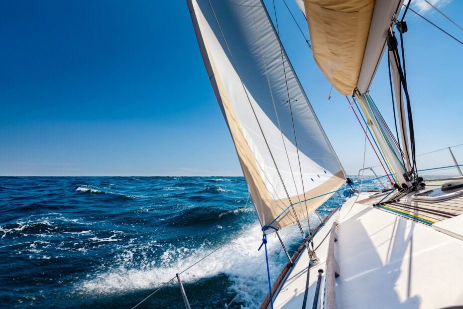 Looking over the side of a white sailing boat at open sea in sunshine