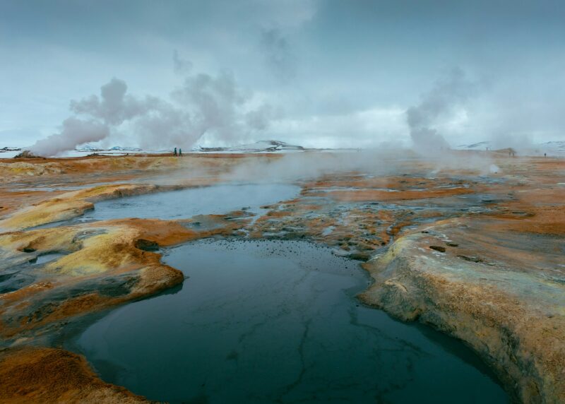 hot pools with steam rising surrounded by an arid desert landscape