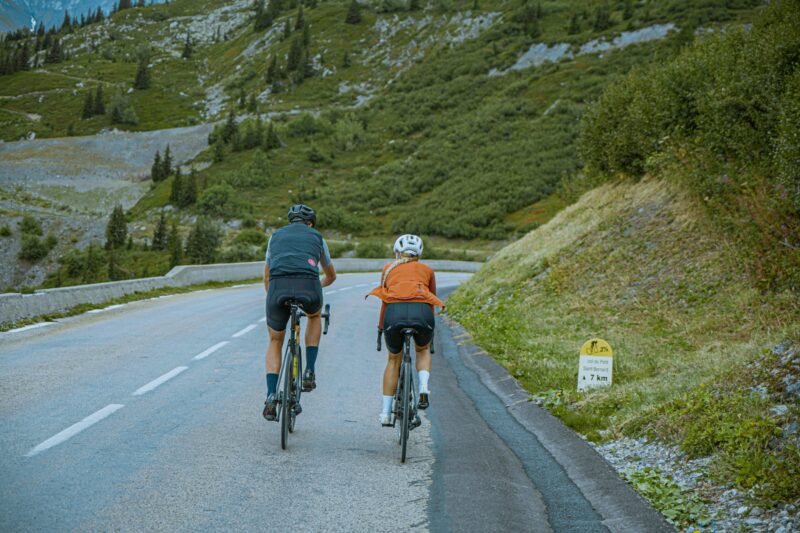 Man and woman riding bikes on a road with cliffs around them