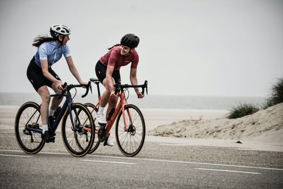 Man and woman riding bikes on a road with sea behind