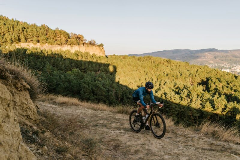 Person riding a bike down a hill with forest behind