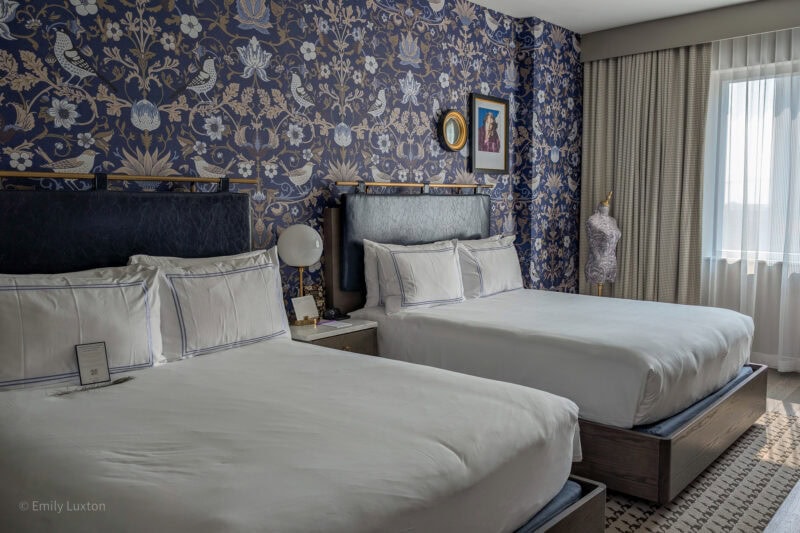 Bedroom in the Dorian Hotel Calgary with two double beds and blue flower patterened wallpaper