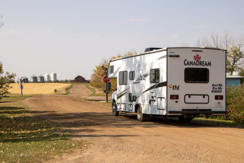 Large white CanaDream motorhome on a road in Alberta with farmland and grain pillars ahead | Alberta 1 week Road Trip