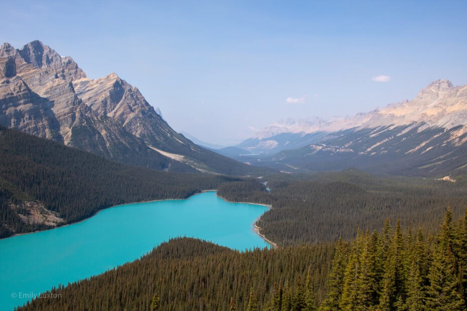 View of a turquoise lake in the shape of a dog surrounded by mountains