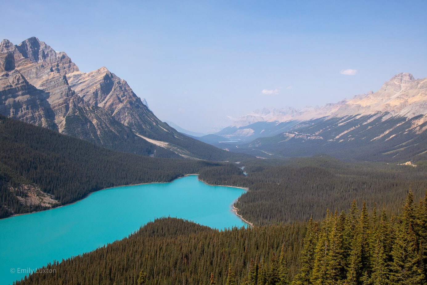View of a turquoise lake in the shape of a dog surrounded by mountains