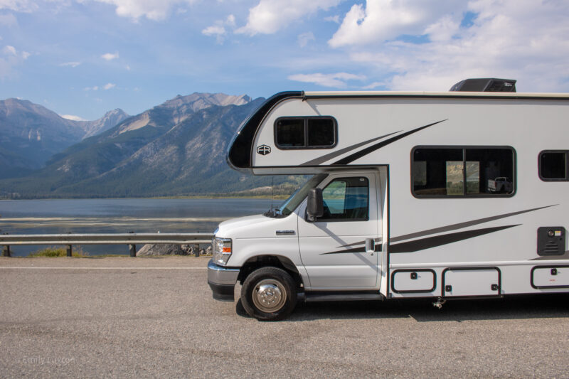 Large white motorhome with a lake and mountains behind | Alberta 1 week Road Trip