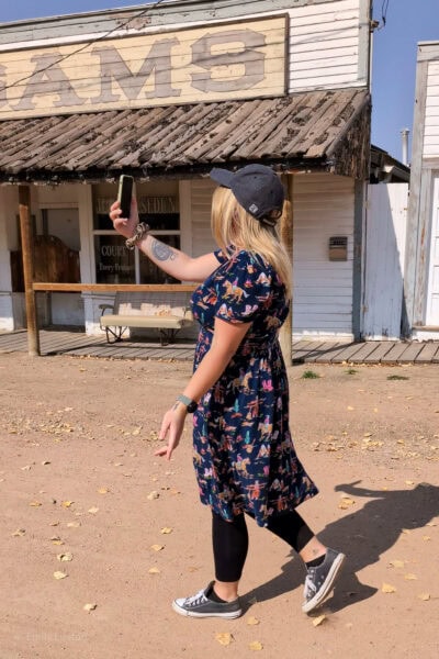 Emily walking next to a wild west style saloon talking into her phone