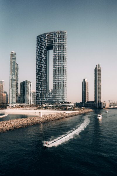 skyscrapers in Dubai next to the sea with a jet ski speeding in front of the shore