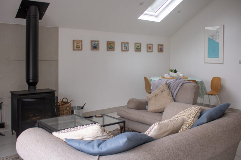 Interior of a holiday lodge with white walls, 2 cream sofas, and a log burner