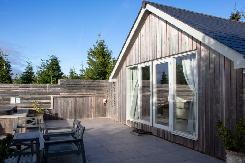 Exterior of a holioday lodge built from light grey wood