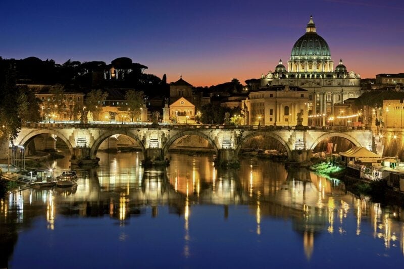 bridge and domed basilica in Rome lit up at night