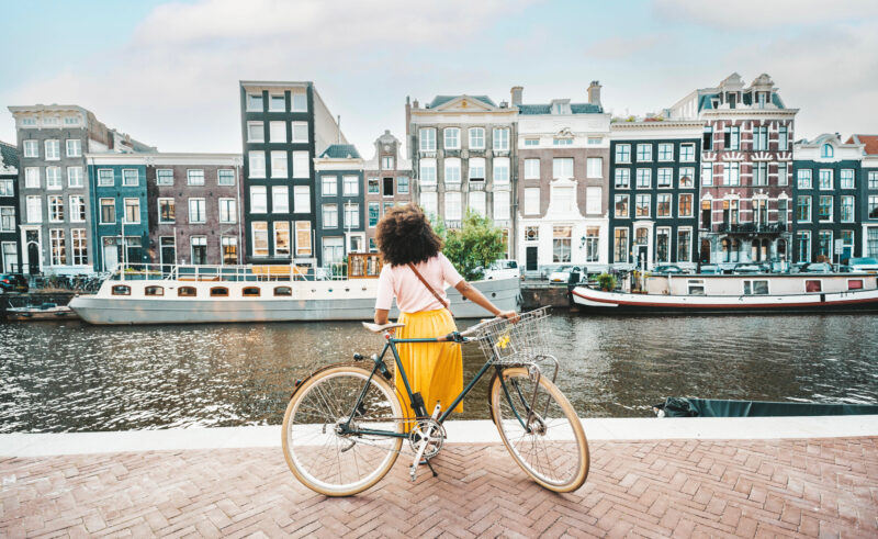 woman with a bike next to a canal in amsterdam