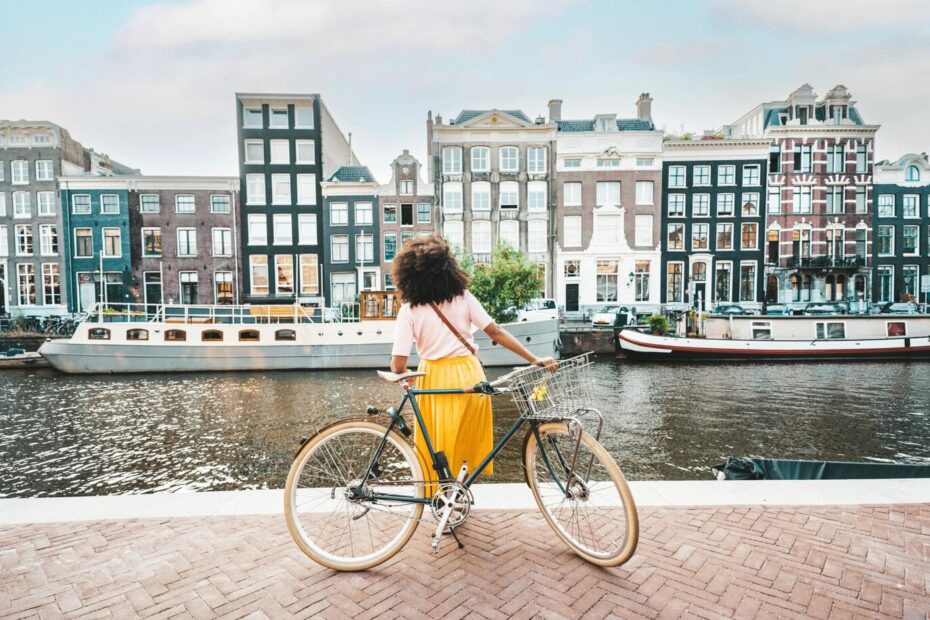 woman with a bike next to a canal in amsterdam