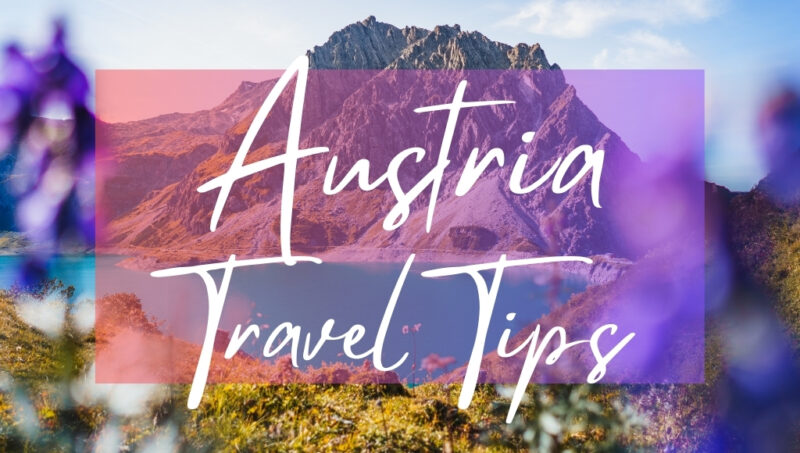 Austria Travel Tips written in white text over an opaque pink box on top of a photo of a lake with a mountain and purple flowers