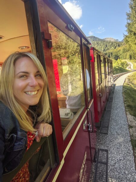 emily looking out the window of a red train carriage