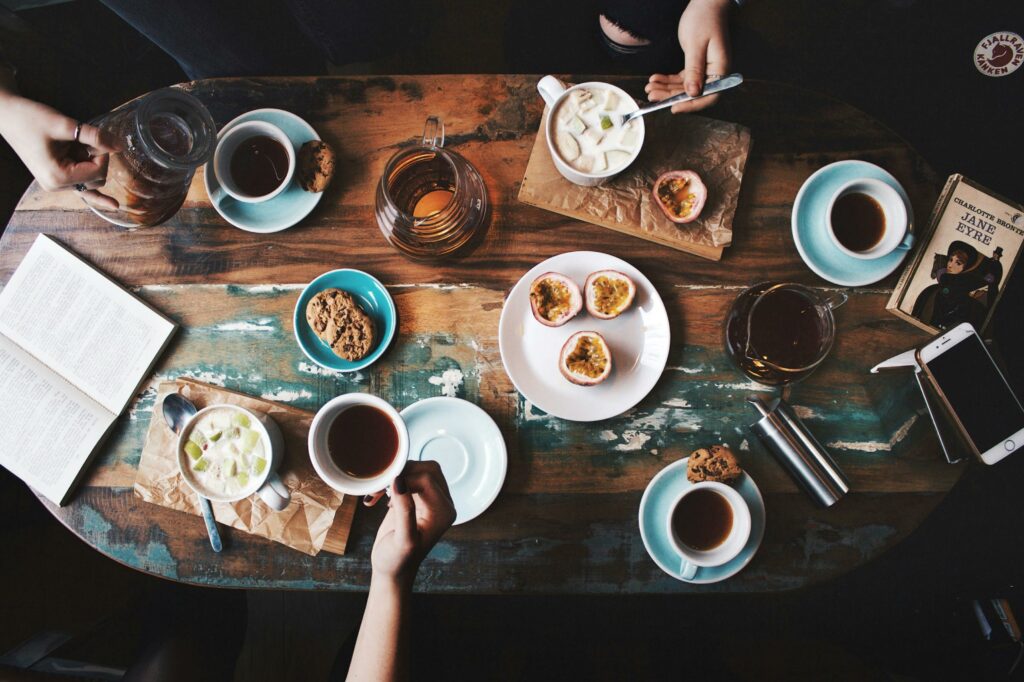 flay lay of a loaded table in a cafe with hands holding coffee