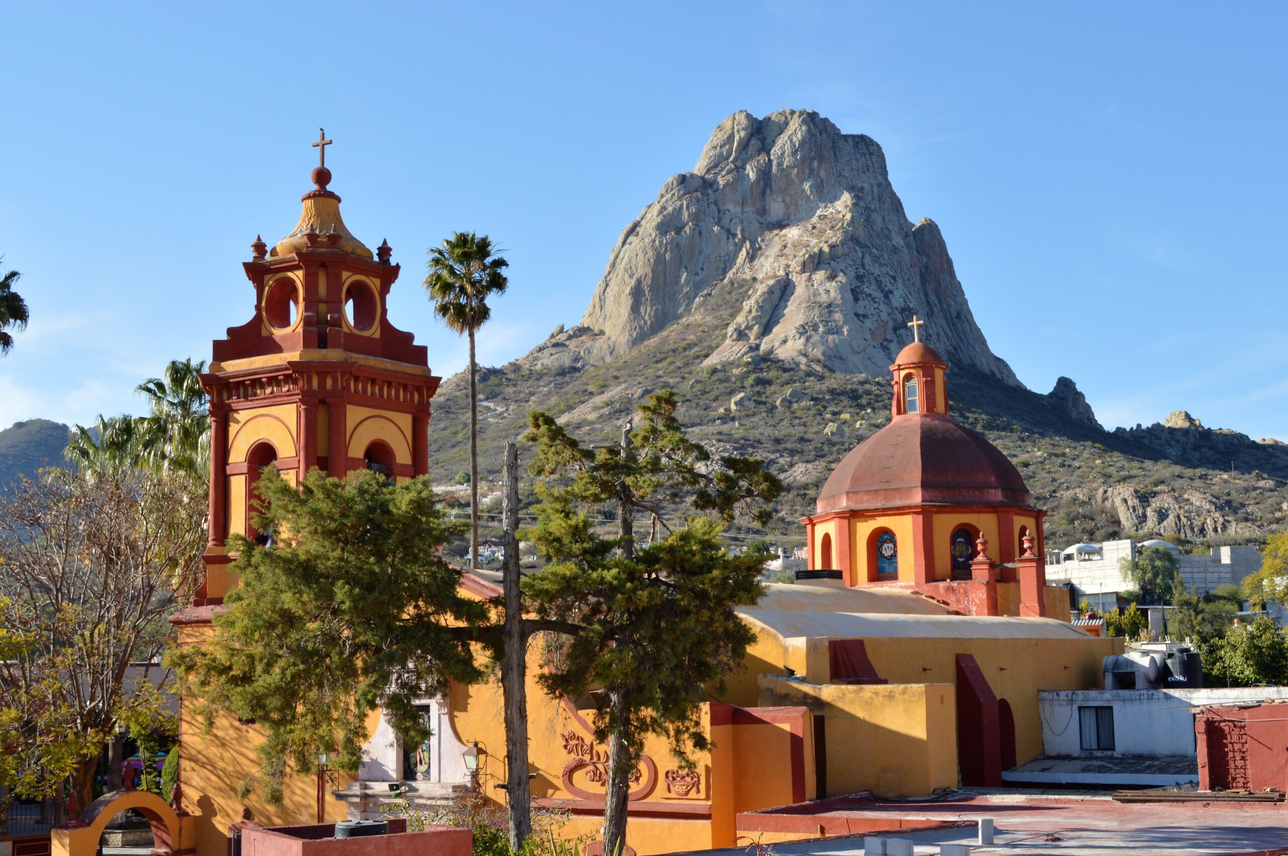 toll monolithic rock mountain behind a yellow church