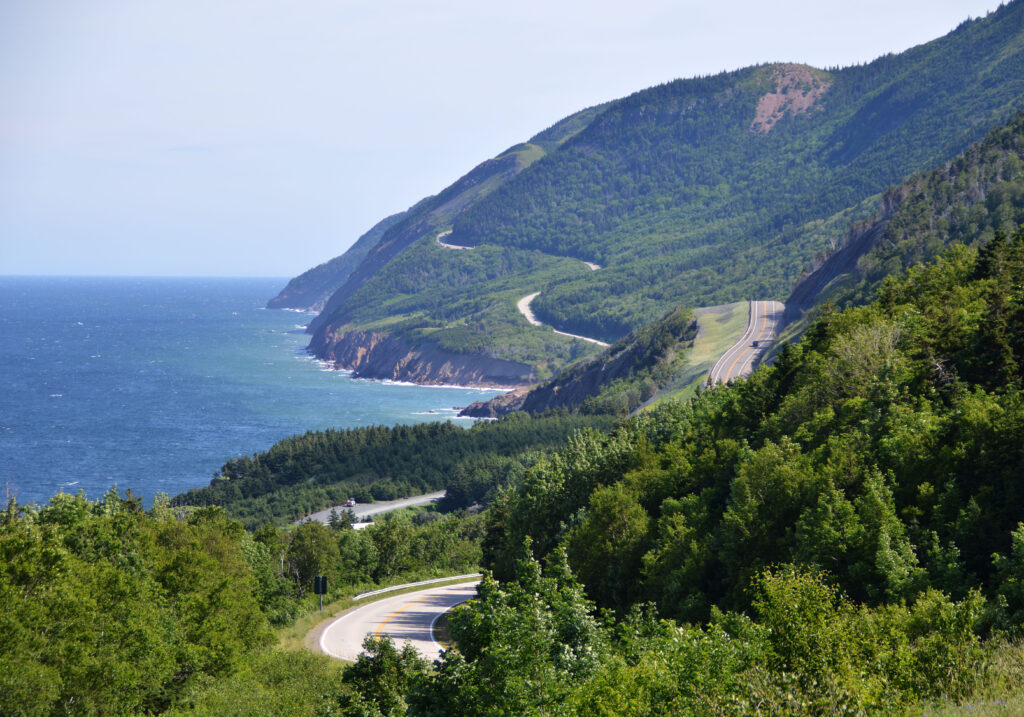 aerial view of a winding road following the shoreline next to the sea