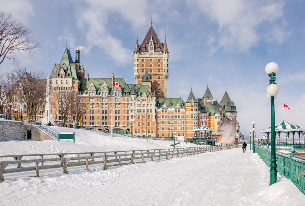 A palace built from orange stone with many towers, next to a road covered in snow