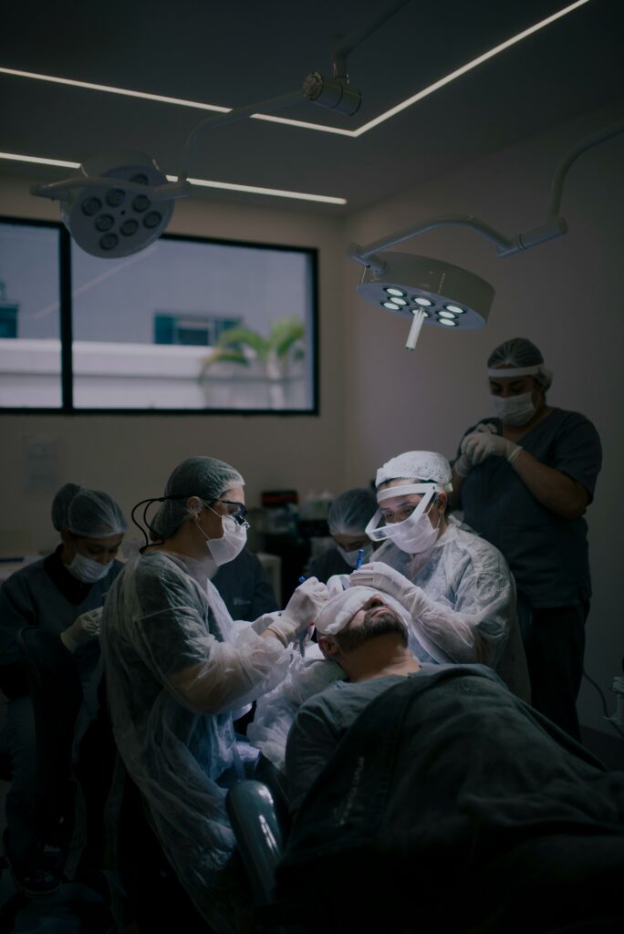 Photo of a Man Getting a Hair Transplant Surgery, surrounded by 5 people in scrubs and ppc