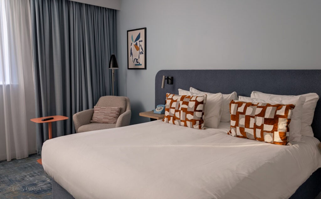 Hotel bedroom with a large white bed with orange cushions