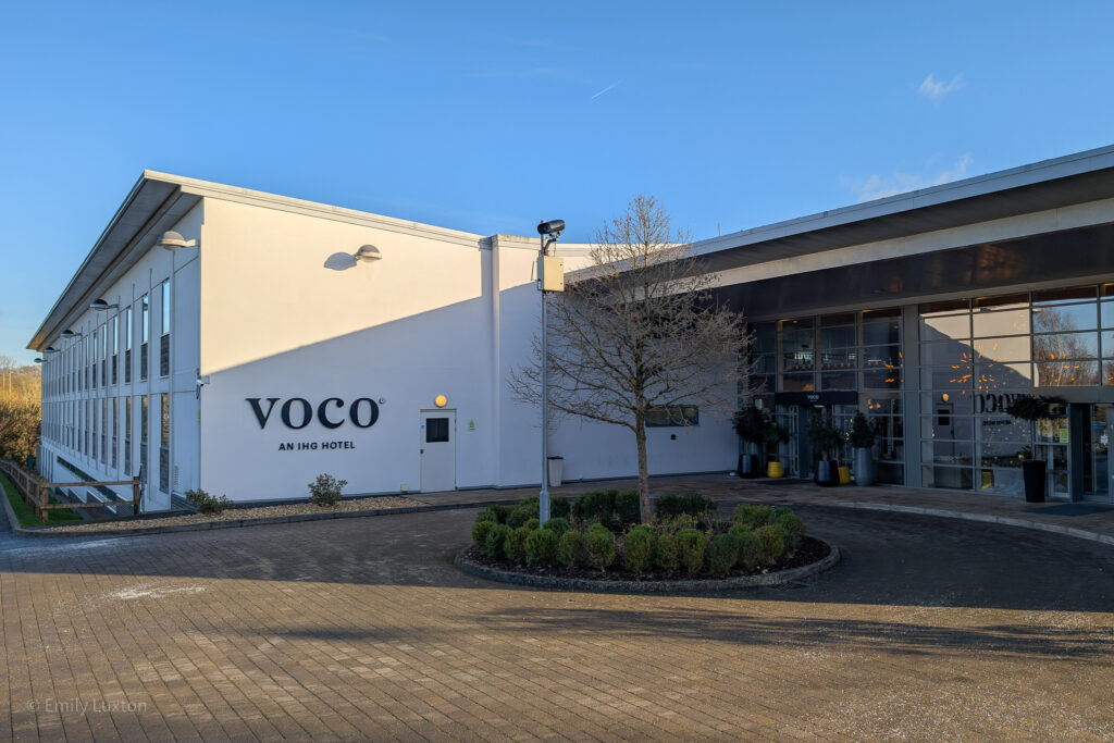 Exterior of voco Winchester hotel and spa on a sunny day with clear blue sky