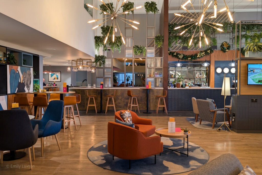large hotel lounge space with different coloured armchairs and a bar