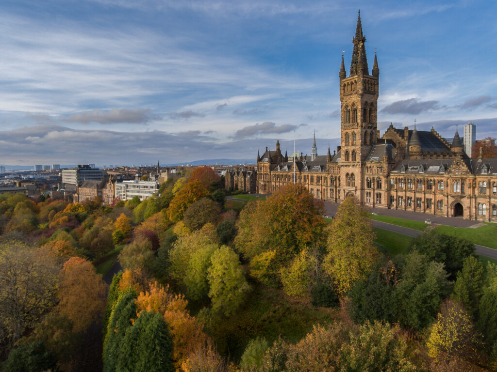 aerial view of a park with many trees in front of a large castle like building at Glasgow University 