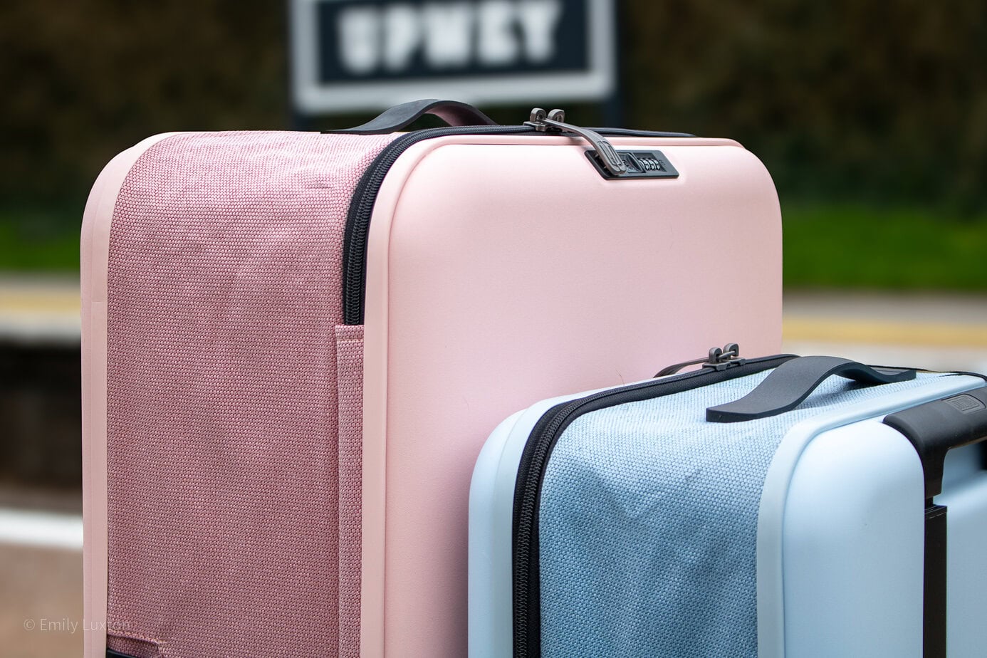 A large pink and small blue hardshell suitcase on a train station platform | JOLLYING Pebble Review