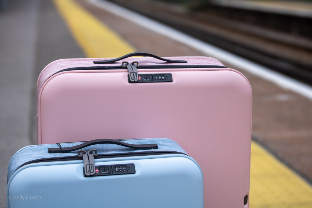 Tops of a large pink and small blue hardshell suitcase on a train station platform | JOLLYING Pebble Review