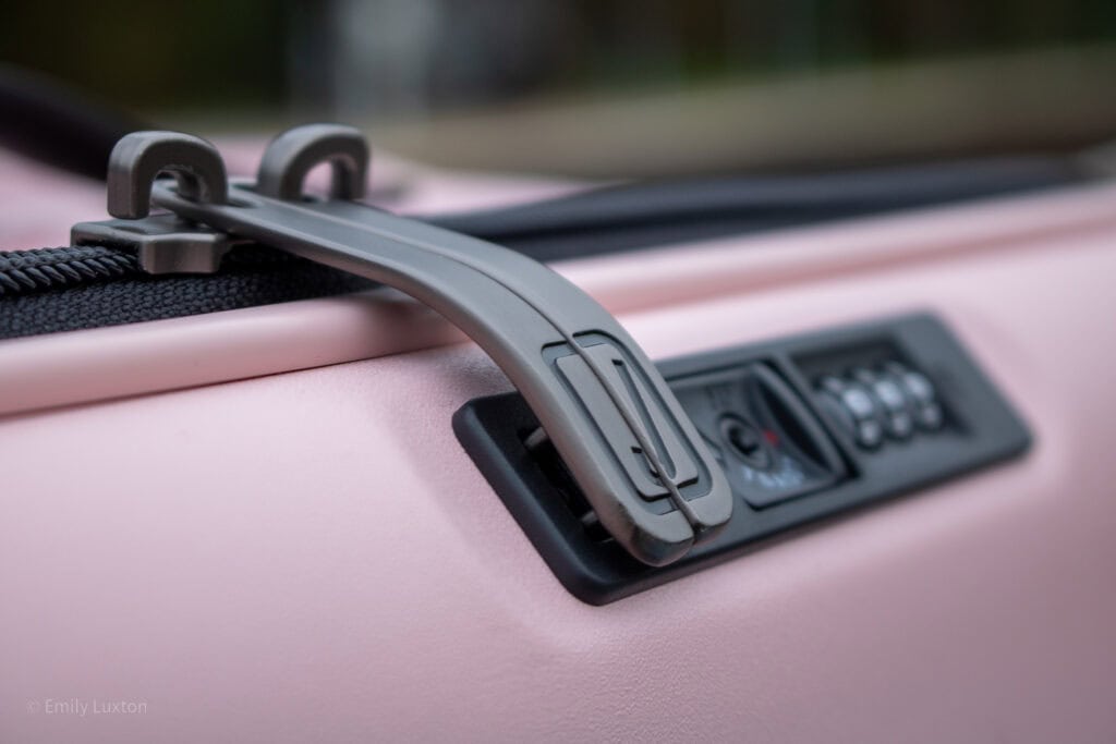 Close up of the zipper pulls of a pink suitcase