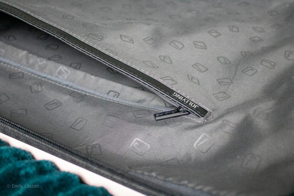 Close up of an open zip pocket in grey fabric suitcase lining