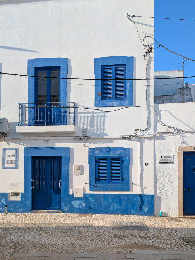 Whitewashed building with blue doors and blue paint around the windows