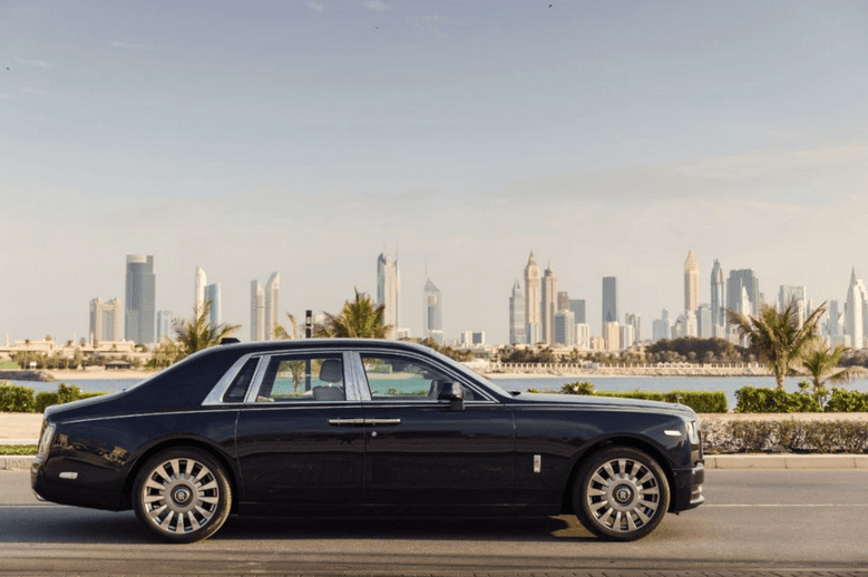 black estate car driving on a road with Dubai city skyline in the distance