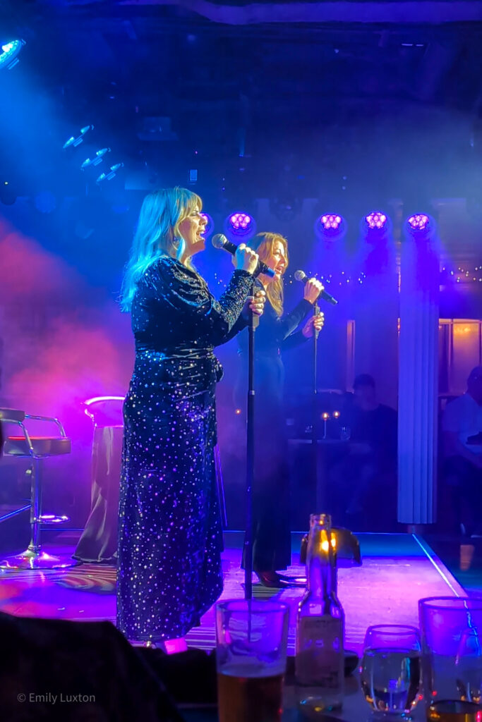Two women on a stage singing into microphones