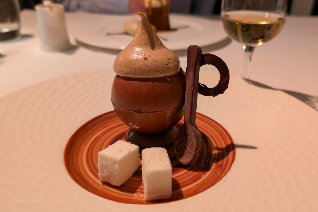 chocolate tea cup on a white plate with sugar cubes