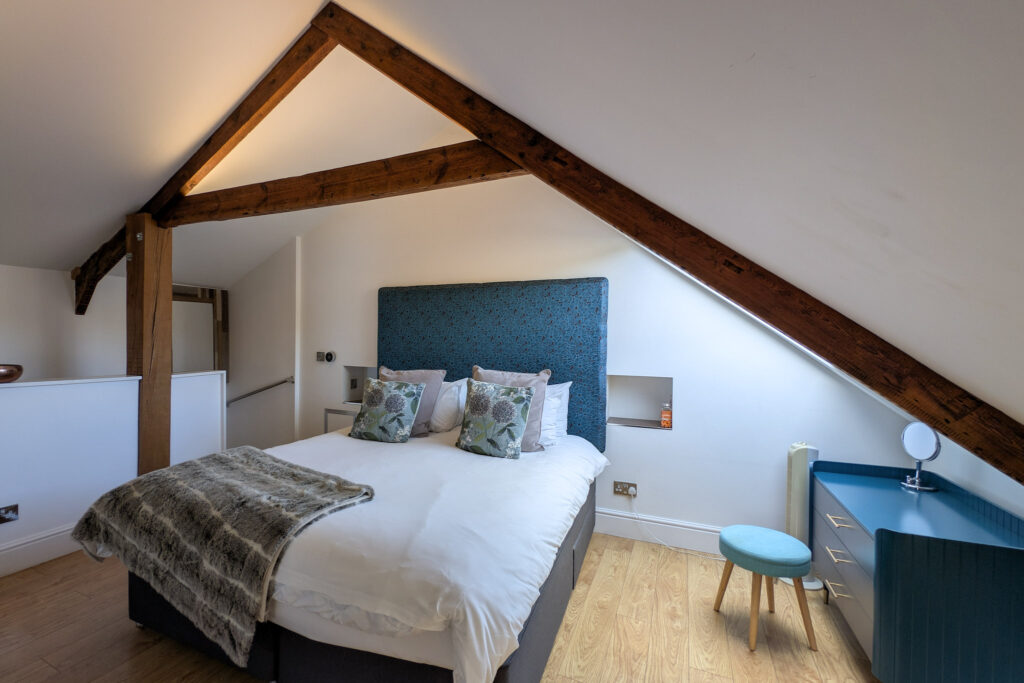 Double bed in a loft bedroom with sloping ceilings and wooden beams