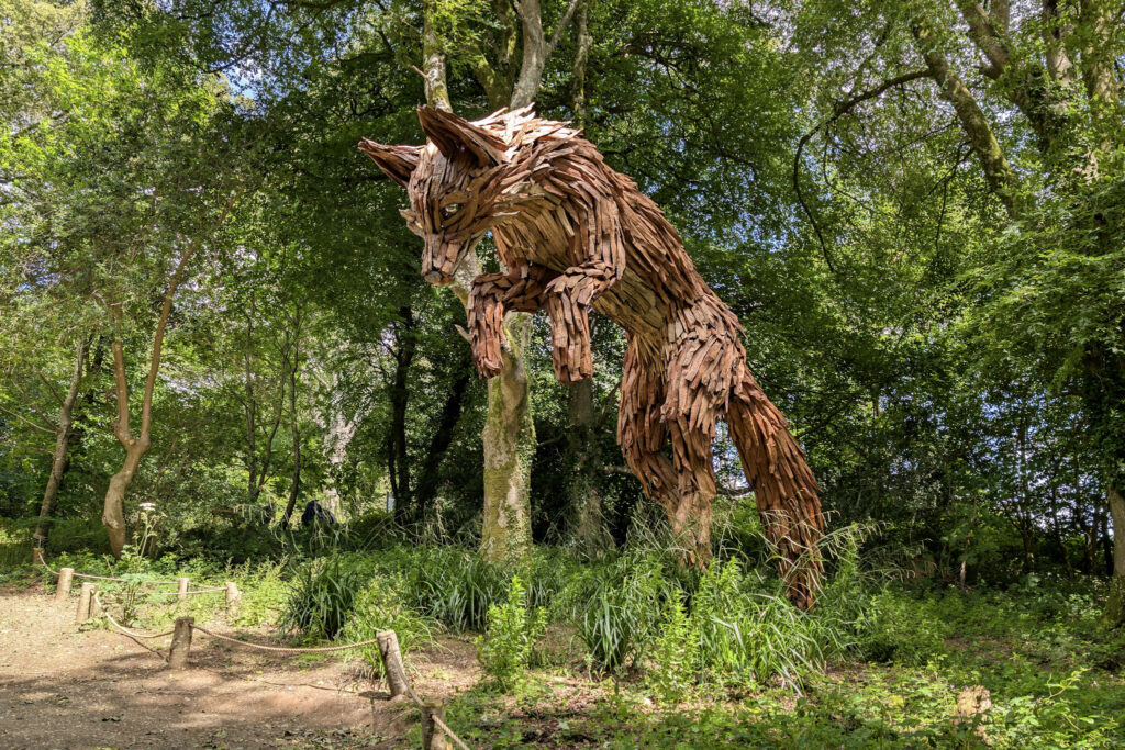 Large wooden sculpture of a leaping fox in a forest