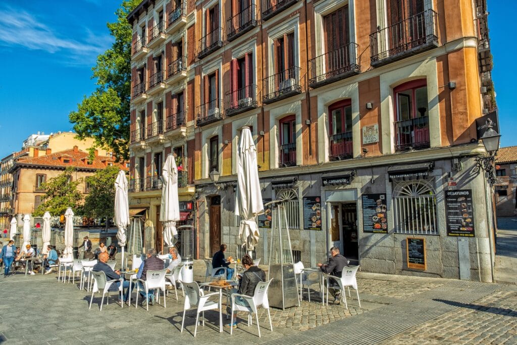 Tables with umbrellas outside a bar in a city street in madrid