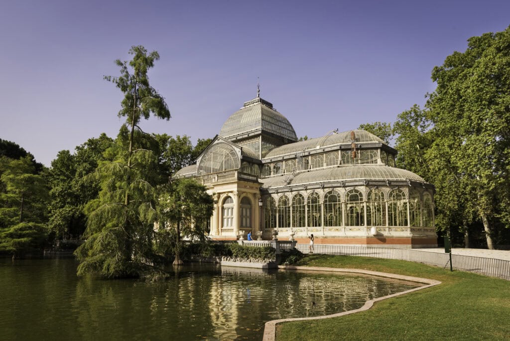 Palacio de Cristal, a large glasshouse by a lake in Retiro Park 