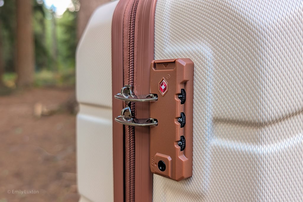 Close up of 2 zips in a brown TSA lock wheel on a cream and brown suitcase
